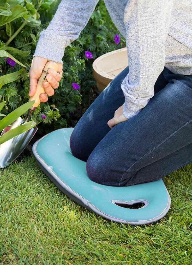 Garden kneeler bench with a clip-on umbrella shading a gardener while weeding a flower bed