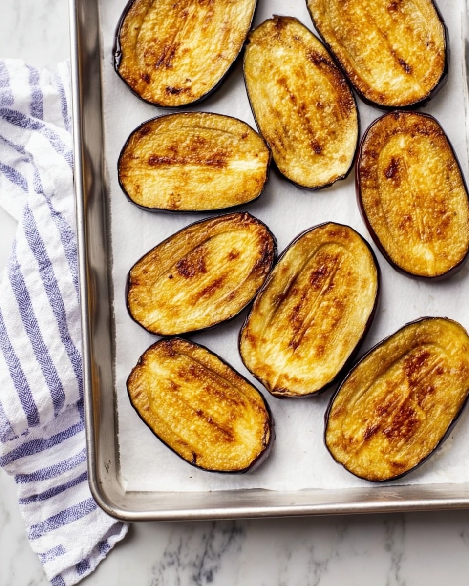 Sliced eggplant arranged in a single layer on a baking tray before roasting
